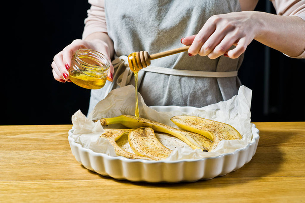 Шеф-кухар п'є шматочки меду з бананів у випічці. Приготування смажених бананів. Чорний фон, вид збоку, кухня
 - Фото, зображення