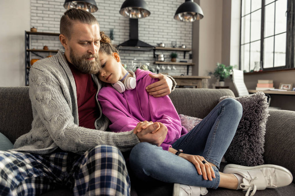 Daughter wearing jeans and sneakers leaning on shoulder of father - Foto, afbeelding