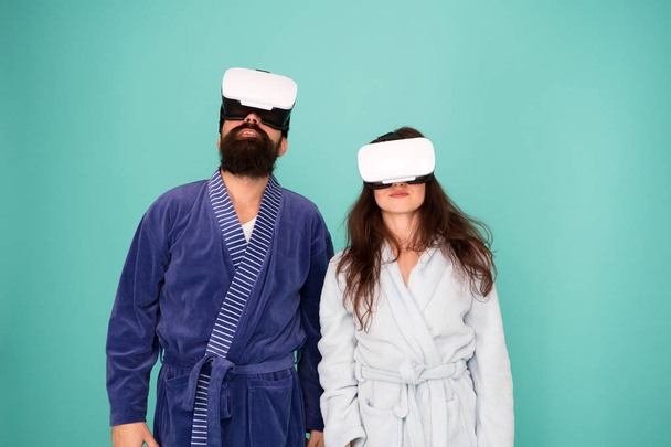 Awakening from virtual reality. Couple in bathrobes wear vr glasses. Conscious awakening. Return to reality. Man and woman explore vr. VR technology and future. VR communication. Exciting impressions - Foto, Imagen