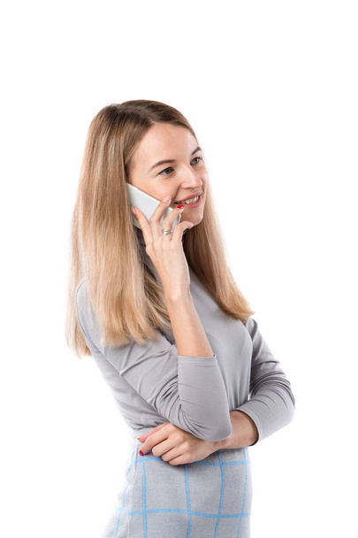 The theme of a business woman and telephone conversations. Beautiful young caucasian woman uses a smartphone handset to call in formal clothes on a white isolate background - Photo, image