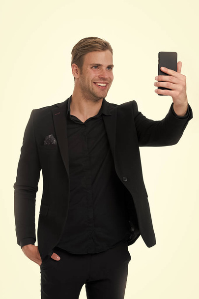 Happy to see you. Business man smartphone video conferencing isolated white. Businessman smiling face video call. Businessman black suit take advantages of video conferencing. Streaming video online - Foto, imagen