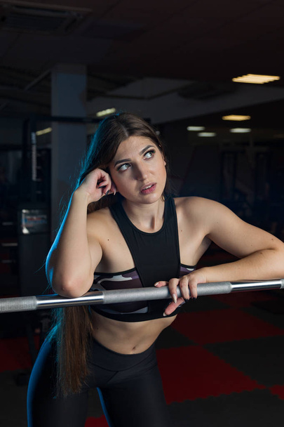 Όμορφη σέξι γυμναστήριο μοντέλο ποζάρει συναισθηματικά στο αθλητικό barbell στο γυμναστήριο. - Φωτογραφία, εικόνα