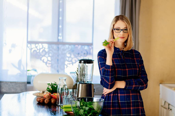 Pregnant woman eating green celery in kitchen - Fotografie, Obrázek