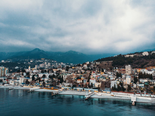 Luftpanoramablick auf Yalta Stadtdamm mit Meer bei bewölktem Wetter, Berge und Wellenbrecher, schöner Urlaubsort - Foto, Bild