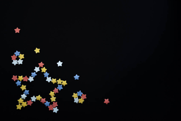 Estrela dobrada de estrelas de pastelaria de açúcar multicoloridas em um fundo preto com copyspace
 - Foto, Imagem