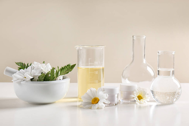 Productos para el cuidado de la piel, ingredientes y cristalería de laboratorio en la mesa. Investigación dermatológica
 - Foto, imagen