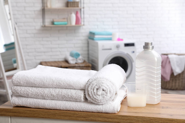 Soft bath towels and detergent on table against blurred background - Foto, Imagen