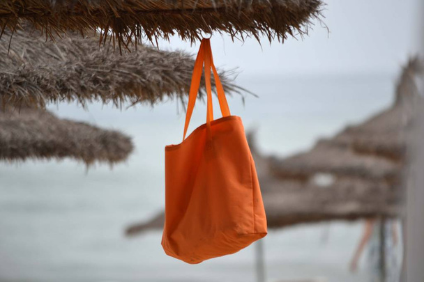 Bolsa colgando en el paraguas de la playa
 - Foto, Imagen