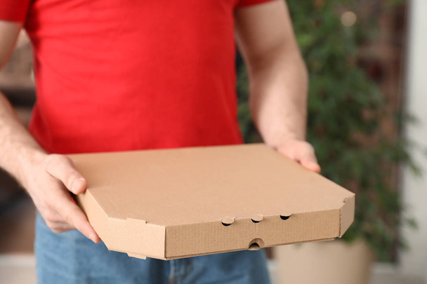 Courier with pizza box on blurred background, closeup. Space for text - Zdjęcie, obraz