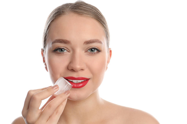 Young woman with ice cube on white background. Skin care - 写真・画像