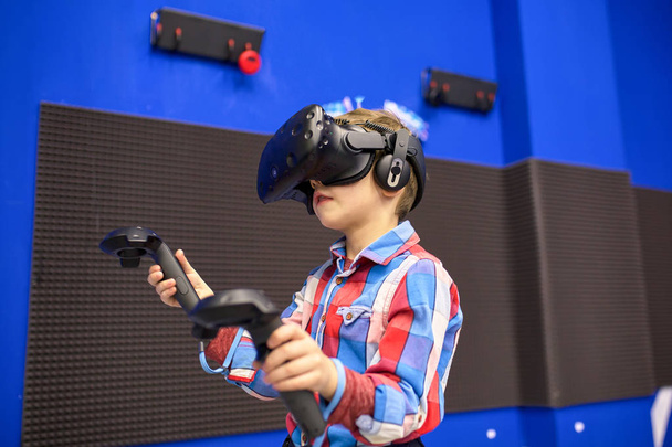 conceito de tecnologia moderna, jogos e pessoas - menino em fone de ouvido de realidade virtual ou óculos 3d jogando videogame no centro de jogos
 - Foto, Imagem