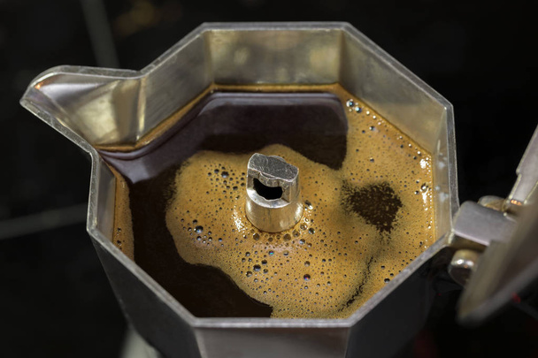 Nahaufnahme einer offenen Mokkakanne Kaffeemaschine über schwarzem verschwommenem Hintergrund. - Foto, Bild