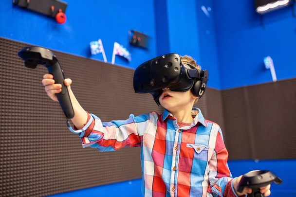 conceito de tecnologia moderna, jogos e pessoas - menino em fone de ouvido de realidade virtual ou óculos 3d jogando videogame no centro de jogos
 - Foto, Imagem