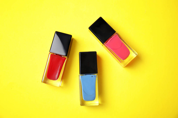 Bottles of nail polish on color background, top view - Photo, Image