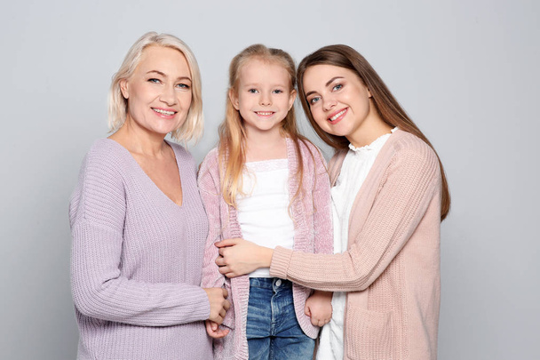 Portrait of young woman, her daughter and mature mother on color background - Foto, immagini