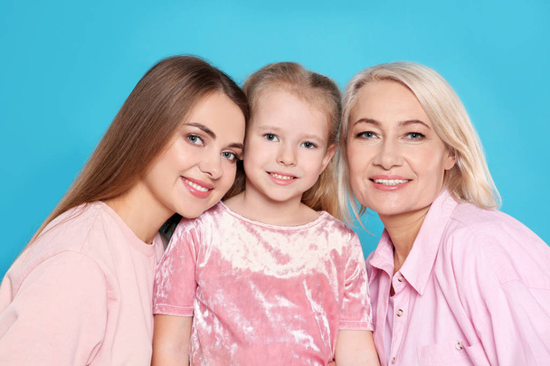 Portrait of young woman, her daughter and mature mother on color background - Фото, зображення