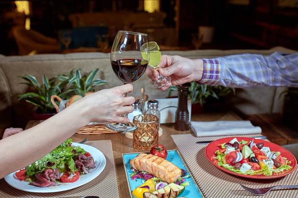 Cena con amigos de la familia servida en un restaurante. Dos copas de vino blanco en las manos
 - Foto, imagen