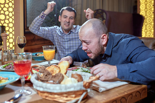 Zwei Männer streiten sich während des Mittagessens in einem Restaurant - Foto, Bild