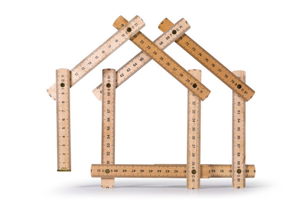 2 軒の家の形をした木製の折りたたみ式メートル定規。白い背景上に分離。クリッピング パスを含める. - 写真・画像