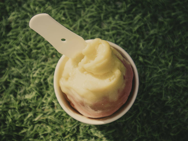 Persone che tengono un cono di gelato al mango e fragola in una giornata estiva soleggiata con sfondo verde
 - Foto, immagini