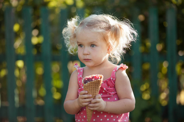 Happy little girl is eating berries in summer garden, outdoor. - Foto, Imagem