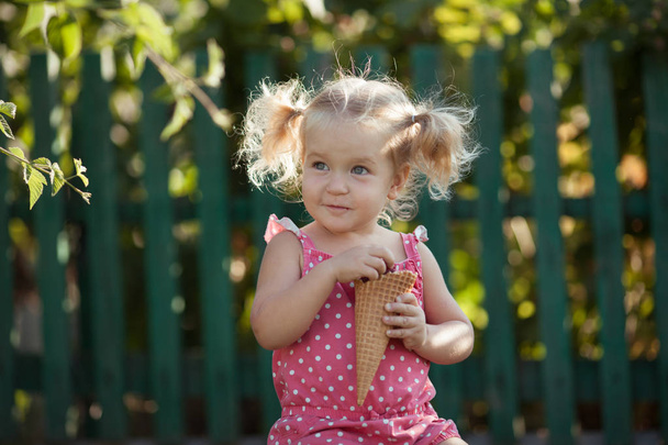 Felice bambina sta mangiando bacche nel giardino estivo, all'aperto
. - Foto, immagini