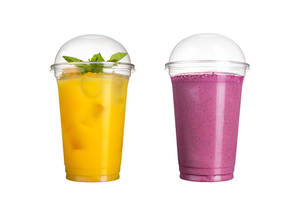 Delicious fruit smoothies in plastic cups, on a white background. Two cocktails with a taste of pineapple and wild berries. - Φωτογραφία, εικόνα