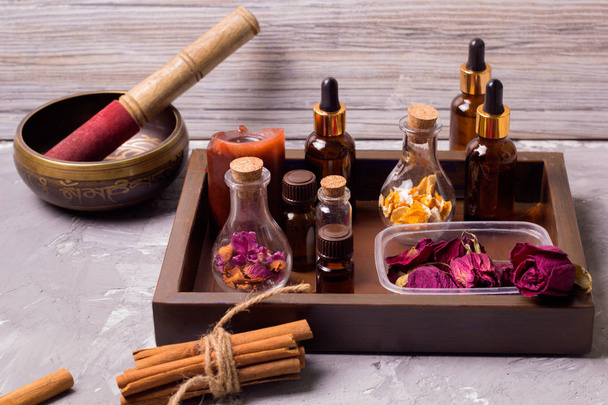 tibetan singing bowl spa set bottles on a vintage wooden tray: dry rose petals,orenge peel,aroma oils,sea salt,cinnamon - Foto, Imagen