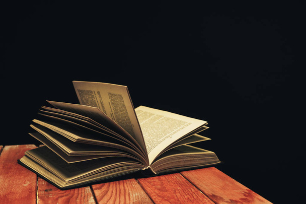 Un viejo libro abierto sobre una mesa de madera roja. Hermoso fondo oscuro
. - Foto, imagen