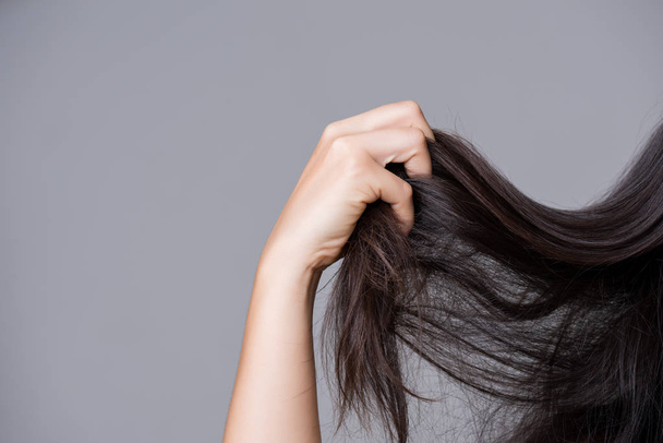 Gezonde concept. Vrouw hand bedrijf beschadigd lange haren. - Foto, afbeelding