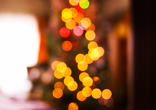 Desfocado ligantes brilhantes de árvore de Natal decorada no interior da casa rural. Desfocado Ano Novo fundo festivo
. - Foto, Imagem