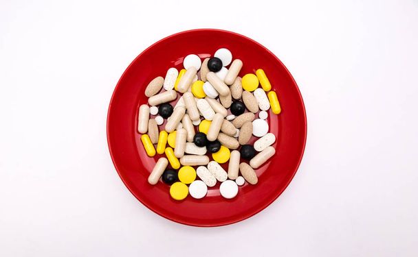 Pharmacy theme Multicolored Isolated medicine and Capsules in red plateon white background - Photo, Image