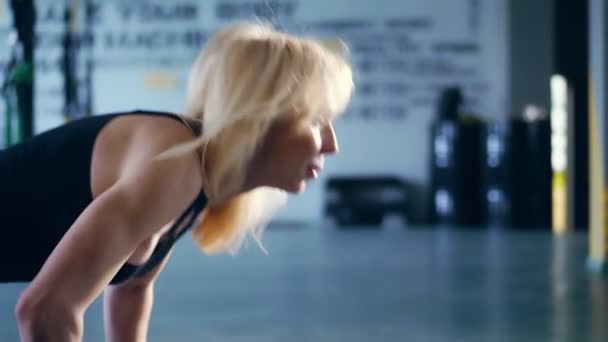 close-up, portrait, attractive blonde woman in black top, doing push ups with flowing hair, performs exercises in the gym. - Footage, Video