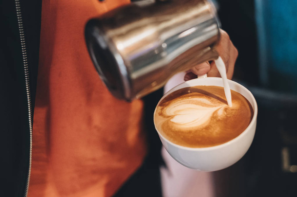 Бариста наливает молоко в кофейную чашку, делая сердце
 - Фото, изображение