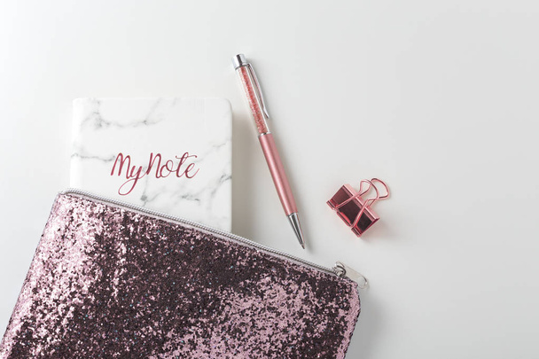 Bolsa de purpurina con bolígrafo y planificador en escritorio blanco
 - Foto, imagen