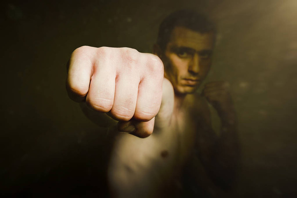 暗い背景に対してキック中男の拳。格闘技の概念、ボクシングのパンチ - 写真・画像