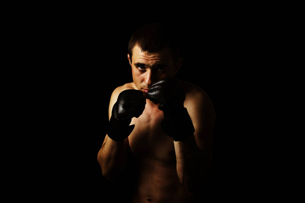 黒の背景に総合格闘技ルールなしの戦いのための手袋の男。ワークアウトの概念、戦闘訓練 - 写真・画像