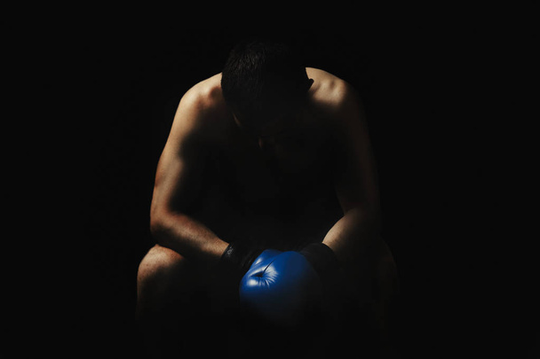 ボクシング グローブで男は暗い背景に対してリングの隅で椅子に座っています。ボクシングの概念、ボクシングのトレーニング、スパーリング - 写真・画像