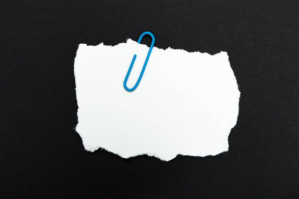 A memo paper clip with a paper clip on a black background. - Photo, image