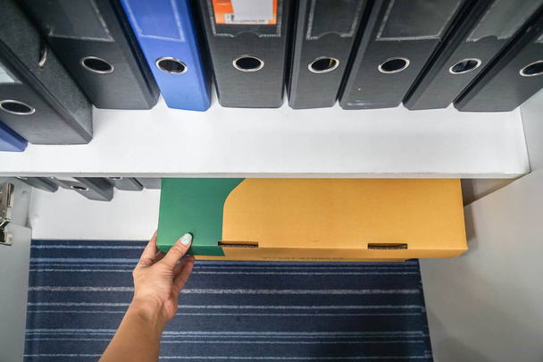 Sekretärin zieht geheime Geschäftspapierbox aus Büroschrank - Foto, Bild