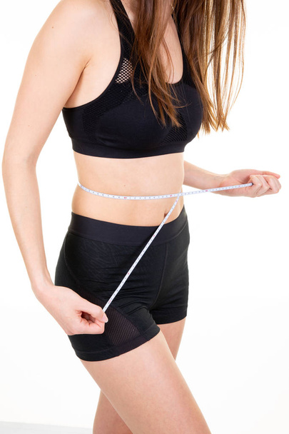 sporty girl taking measurements of her body in white background - Fotó, kép