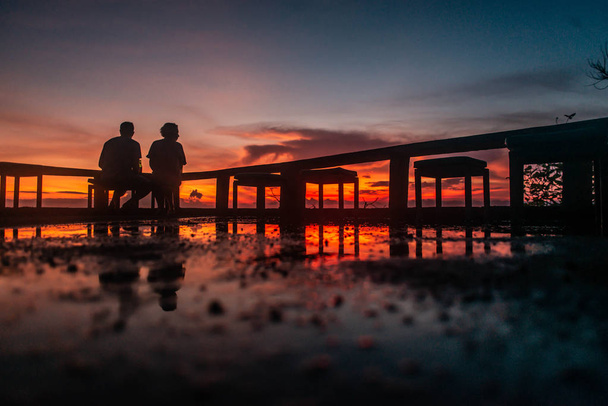 date of a loving couple seat on backgrond of amazing scarlet sun - Φωτογραφία, εικόνα