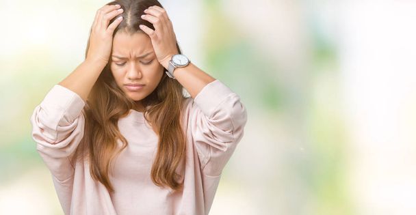 Young beautiful brunette woman wearing pink sweatshirt over isolated background suffering from headache desperate and stressed because pain and migraine. Hands on head. - Photo, Image