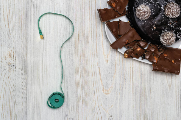 Čokoládový dort, kousky čokolády na desku anda krejčovským metrem v podobě pohledu shora otazník. Byt leží. Kopírovat prostor - Fotografie, Obrázek