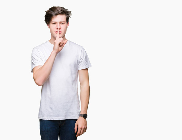 Young handsome man wearing casual white t-shirt over isolated background asking to be quiet with finger on lips. Silence and secret concept. - Fotografie, Obrázek