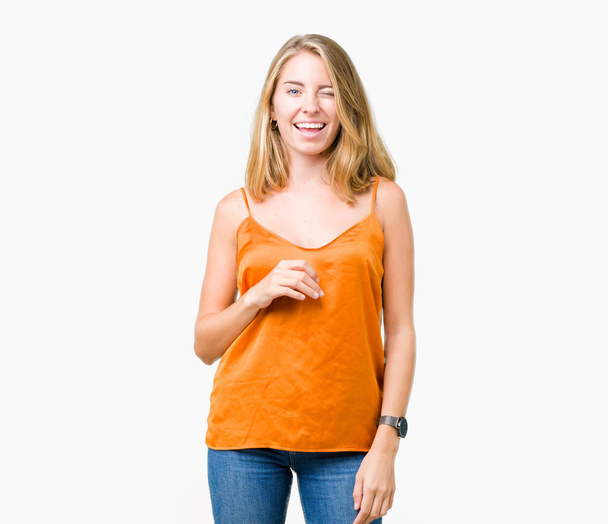 美しい若い女性のセクシーな表情、明るく、幸せな顔でカメラを見てウィンクしている分離の背景にオレンジ色のシャツを着て. - 写真・画像