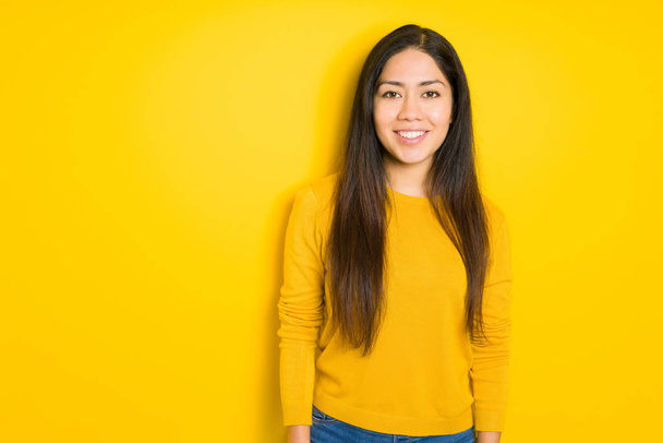 Beautiful brunette woman over yellow isolated background with a happy and cool smile on face. Lucky person. - Zdjęcie, obraz