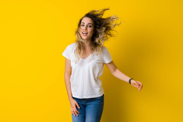Hermosa joven rubia saltando feliz y emocionada sobre un fondo amarillo aislado
 - Foto, Imagen