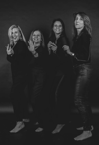 Τέσσερις φίλοι που θέτουν σε ένα στούντιο με ένα μαύρο φόντο - Φωτογραφία, εικόνα