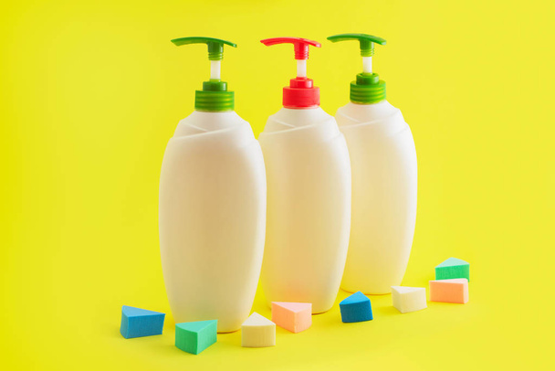 Tres botellas de plástico con dispensador sobre fondo amarillo
. - Foto, Imagen